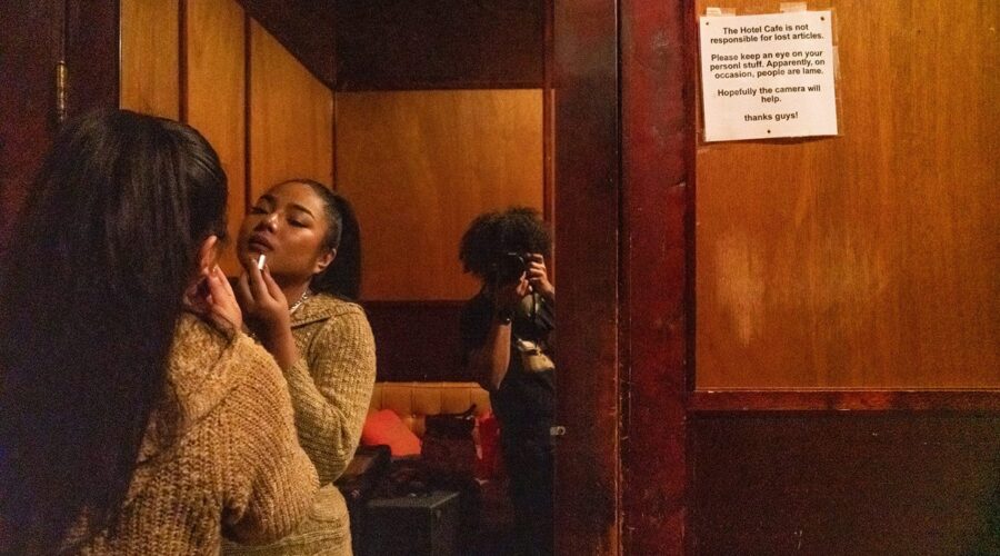 Woman applying lipstick in mirror reflection.